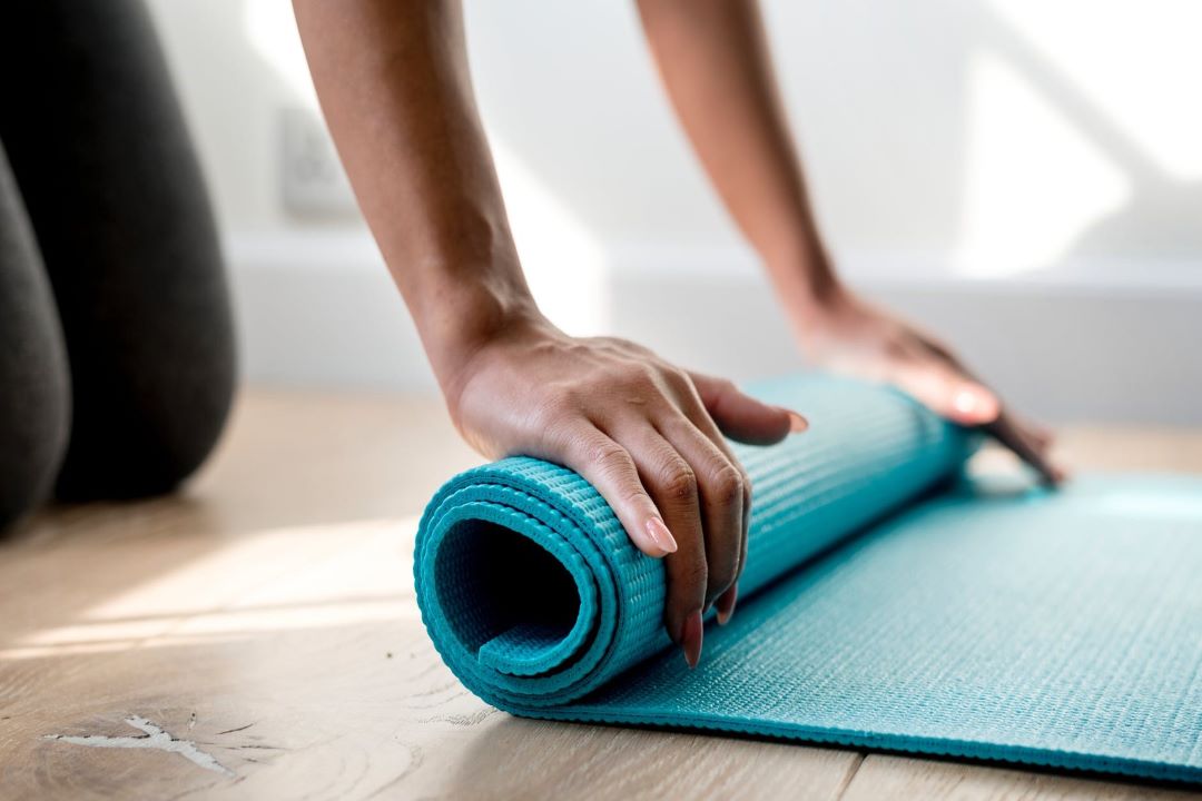 femeie care își rulează covorul de yoga